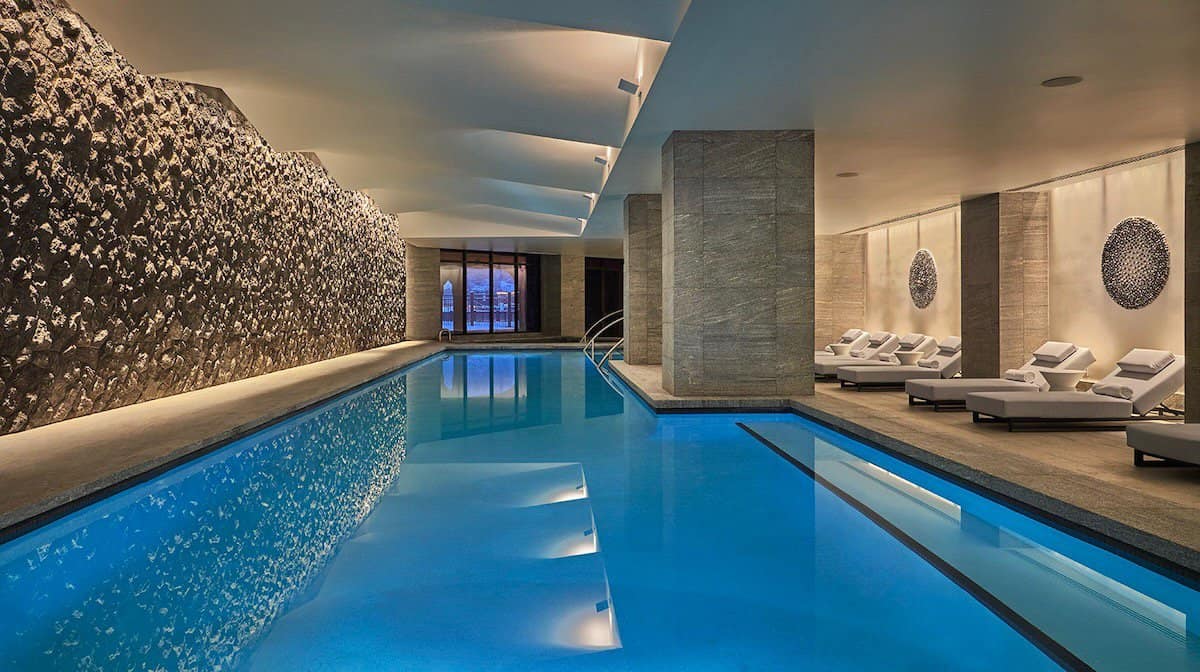 Indoor pool with loungers and dim lighting