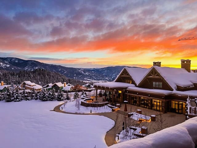 Aerial view of snowy mountain cabin at sunset