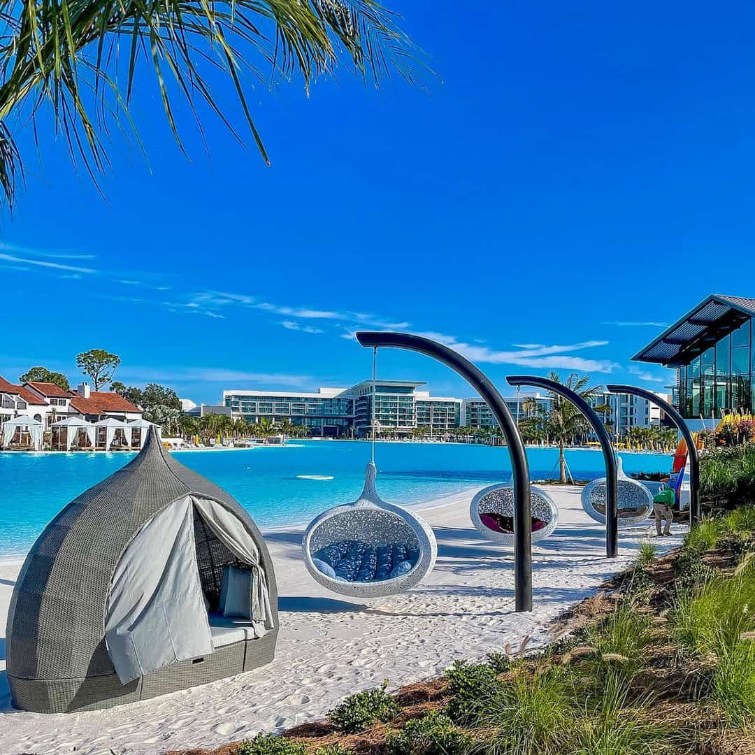 private cabanas and hanging chairs with backdrop of outdoor pool at Evemore Orlando Resort
