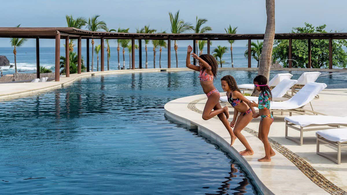young girls jumping into a swimming pool at Four Seasons Resort Punta Mita