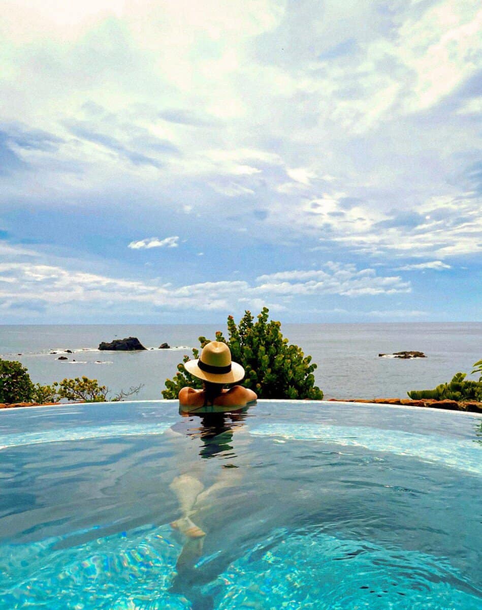 woman with hat overlooking the ocean from a swimming pool at Four Seasons Resort Punta Mita