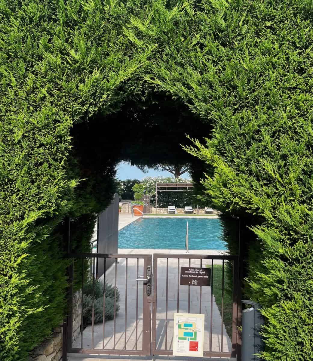 grassy archway with a swimming pool in the backdrop