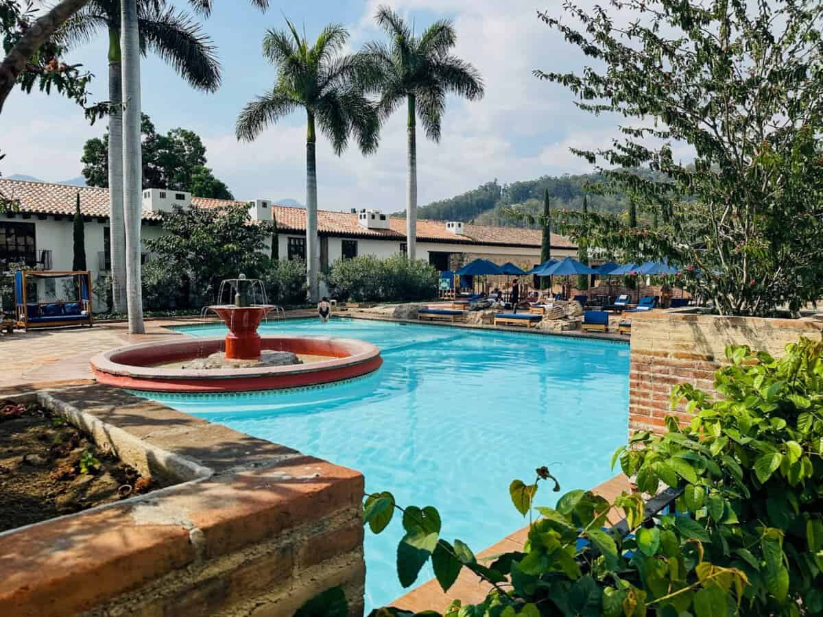 outdoor swimming pool with fountain and sun loungers in backdrop
