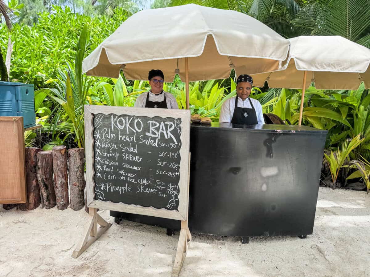 bar stand with two women and a sign saying koko bar at Four Seasons Seychelles Resorts