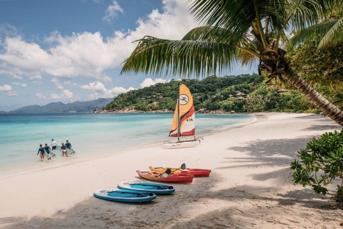 beach with kayaks and sailboat in Seychelles