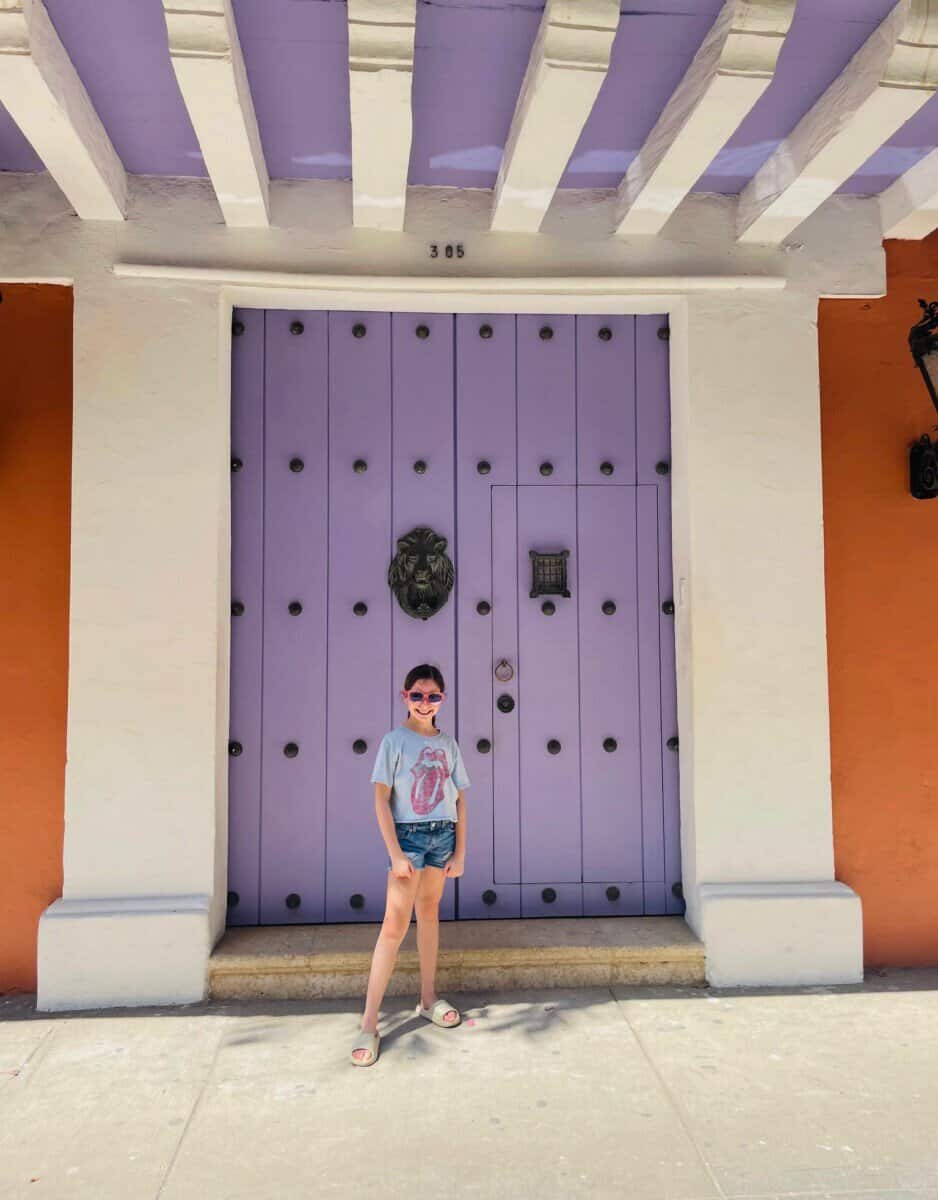 child posing in front of purple door in Cartagena, Colombia