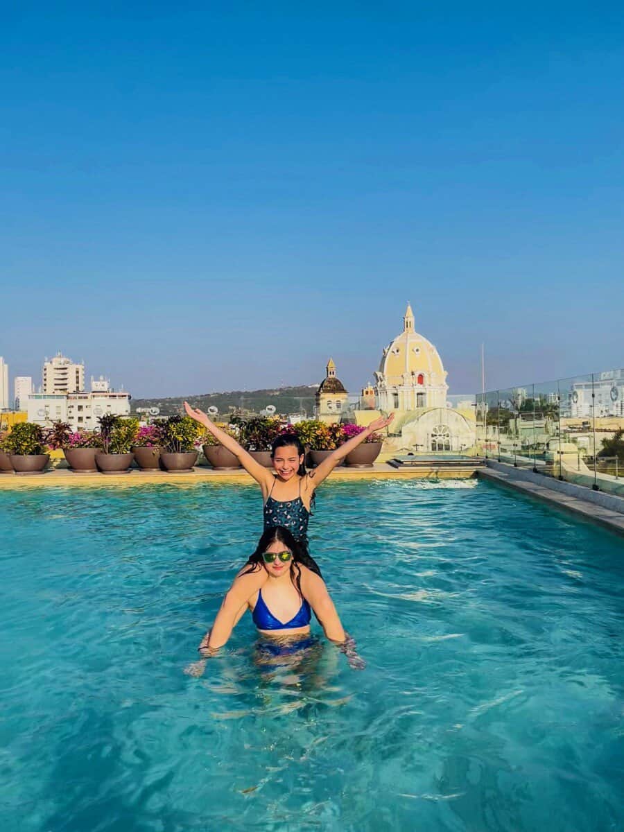 children posing in pool with Cartagena, Colombia city seen in backdrop