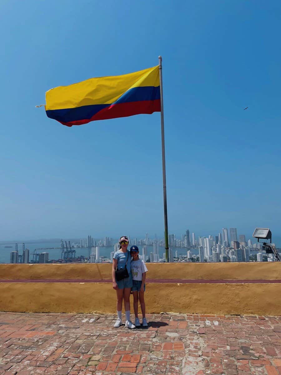 children posing in front of large Colombian flag