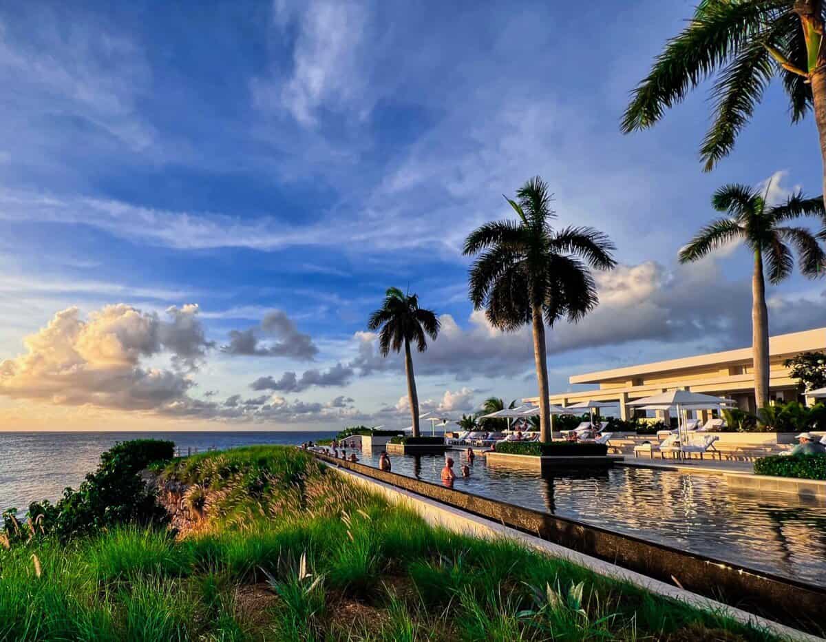 outdoor pool with palm trees and blue skies at Four Seasons Resort Anguilla