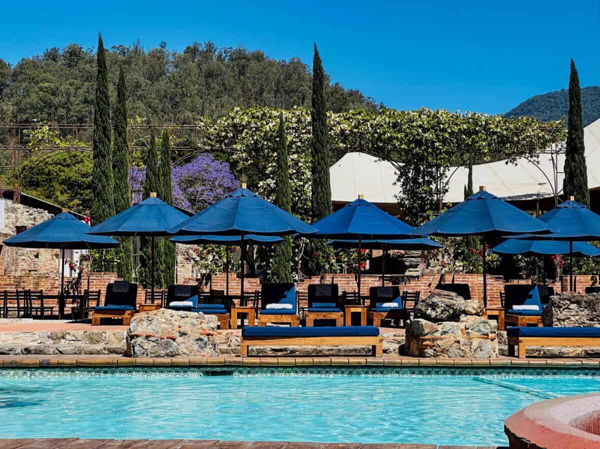 blue umbrellas cover sun loungers lining an outdoor swimming pool in Guatemala