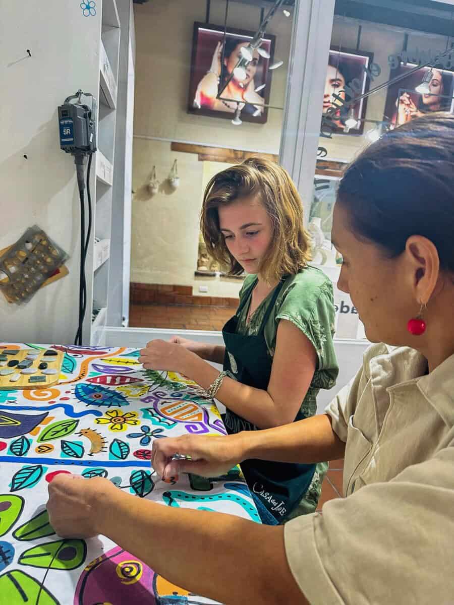 young woman watches a craftswoman in Guatemala