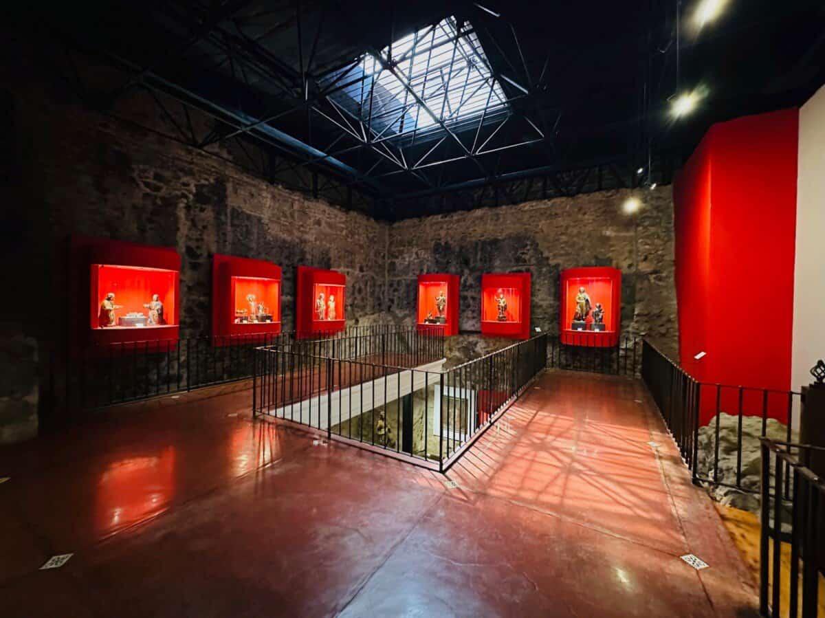large open space with historic statues built in walls with red backdrop in Guatemala